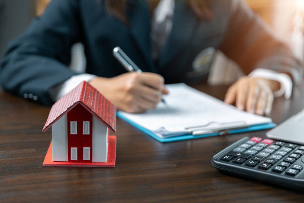istock Discussion with a real estate agent, House model with agent and customer discussing for the contract to buy, get insurance or loan real estate or property. approved mortgage application form. 1803564702