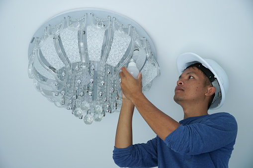 Male technician changing a LED lamp at the customer's house.