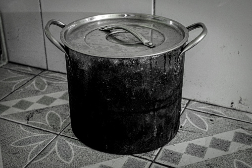 A burnt pan in the kitchen, a dirty pan used for cooking.