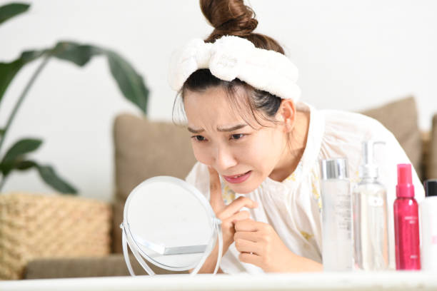 istock A young Asian woman suffering from skin problems looks in the mirror 1803573849