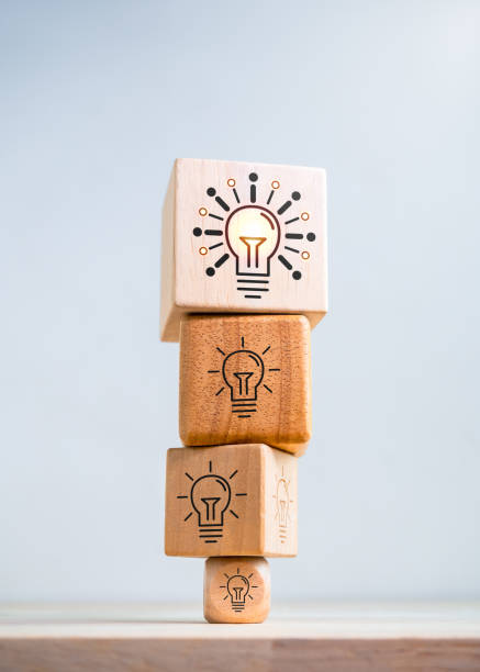 Think big. Inspiration, innovative technology, goal and success concepts. Biggest modern idea lightbulb icon on top of bulbs symbol on smaller wooden cube blocks stack isolated on white background. piensa en grande. inspiración, tecnología innovadora, objetivos y conceptos de éxito. el icono de bombilla de la idea moderna más grande en la parte superior del símbolo de las bombillas en bloques de cubo de madera más pequeños apilados aislados so