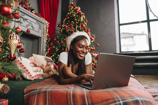 istock Young African woman on bed using laptop on Christmas eve 1803574992