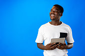 Young african man using digital tablet against blue background
