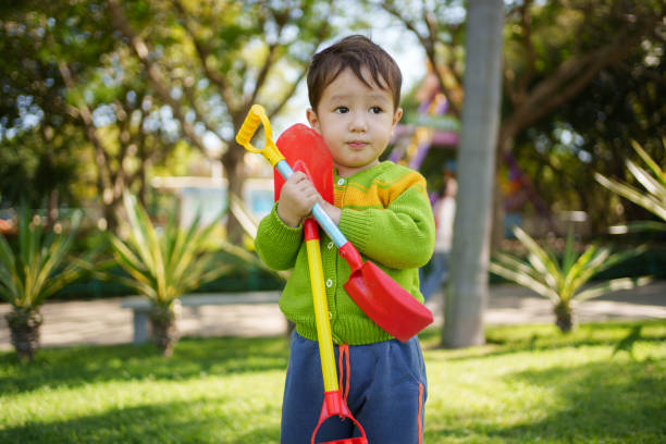 Little boy playing in a dirty drain trench full of trash. \n