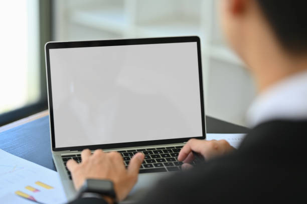 istock Over shoulder view of male financier using laptop at office desk 1803600502