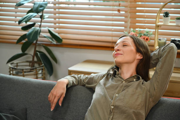 istock Serene young woman with eyes closed relaxing on comfortable sofa at home 1803601076