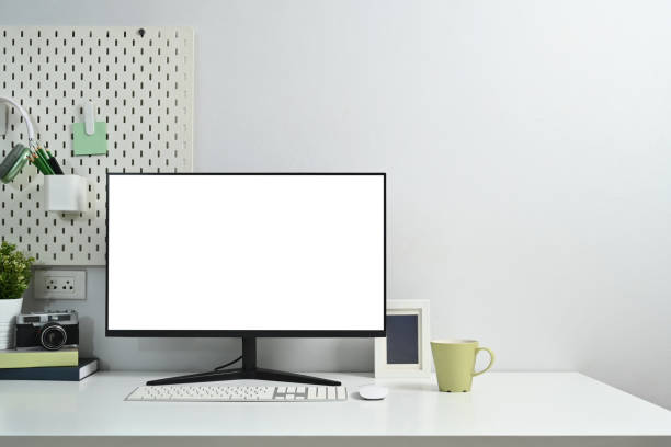 istock Front view computer monitor with blank screen, camera, books and houseplant on white table 1803602156