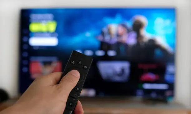Hand holding remote control: binge watching a TV show