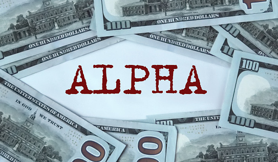 ALPHA - word on the background of cash dollar bills. Alpha is a term used to describe the ability of investment strategies to outperform the market and its edge.