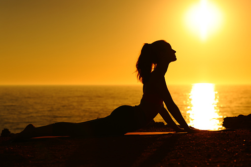 Silhouette of a yogi at sunset doing yoga
