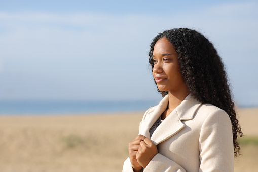 Serious black woman in winter on the beach