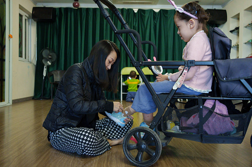 The woman is putting shoes on the child