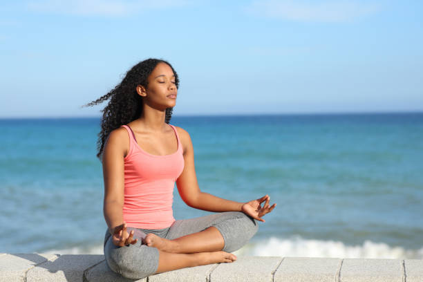 istock Black woman doing yoga exercise on the beach 1803624118