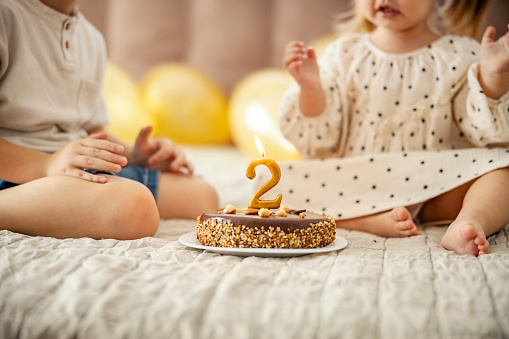 A birthday cake with candle with children celebrating christmas in a blurry background.