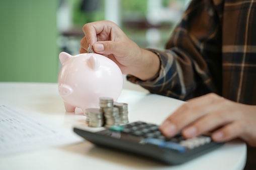 Saving money. hand putting money into pink piggy bank making investments or strategy for personal savings.