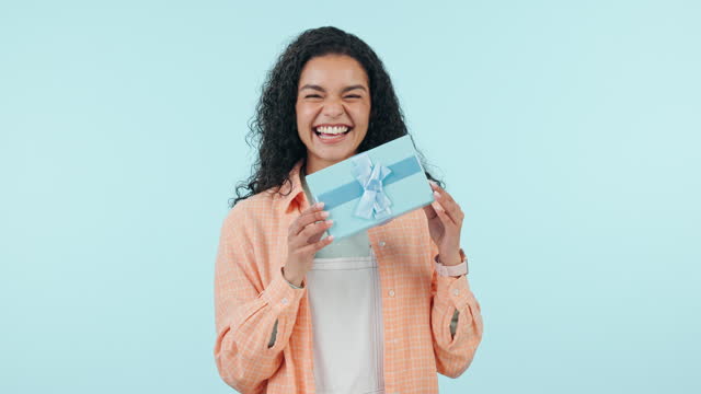 Shake box, excited or happy woman in studio isolated on a blue background with box or product. Face, guess or person with present for party, celebration of holiday or birthday package for giveaway