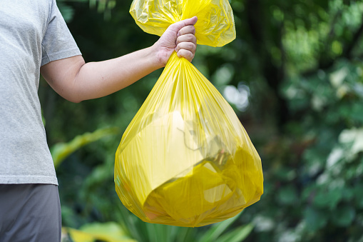 Man Volunteer charity holding garbage yellow bag and plastic bottle garbage for recycling cleaning.