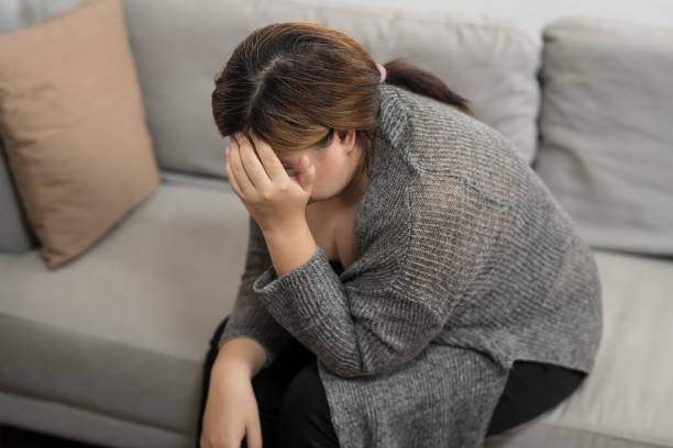 istock Sad Overweight plus size woman thinking about problems on sofa upset girl feeling lonely and sad from bad relationship or Depressed woman disorder mental health. 1803636152
