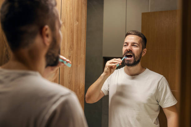 istock Mirror reflection of bearded man brushing his teeth in a bathroom. 1803639589