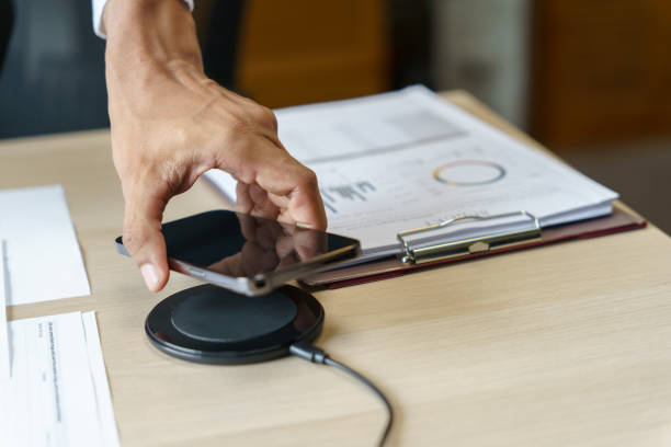 istock Charging mobile phone battery with wireless charging device in the table. Smartphone charging on a charging pad. Mobile phone near wireless charger Modern lifestyle technology concept 1803646889