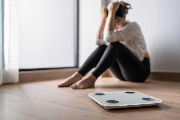 Sad woman with fat upset bored of dieting Weight loss fail Fat diet and scale sad asian woman on weight scale at home weight control Sad woman with fat upset bored of dieting Weight loss fail Fat diet and scale sad asian woman on weight scale at home weight control. photos of anorexia pictures stock pictures, royalty-free photos & images