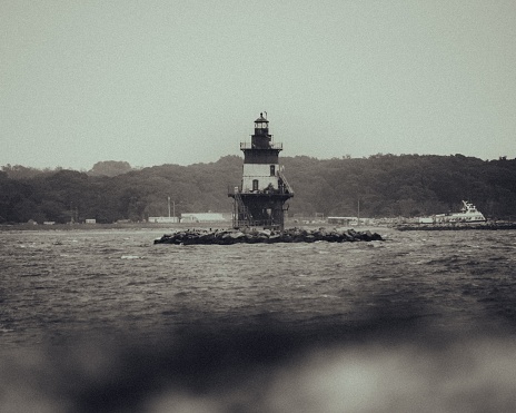 A vintage image of a lighthouse situated at the dock of a harbor, with tranquil waters in the foreground