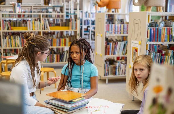 istock Young kids talking with the librarian 1803666855