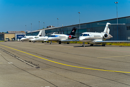 Parked private jets with airport building in the background at Zürich Airport on a sunny spring day. Photo taken June 14th, 2023, Kloten, Canton Zürich, Switzerland.
