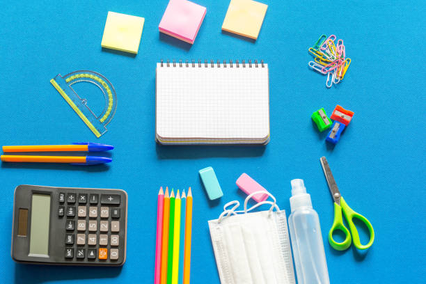 istock Blank graphing paper notebook with school supplies frame against a bright blue wall. Copy space.banner.advertisement. 1803704360