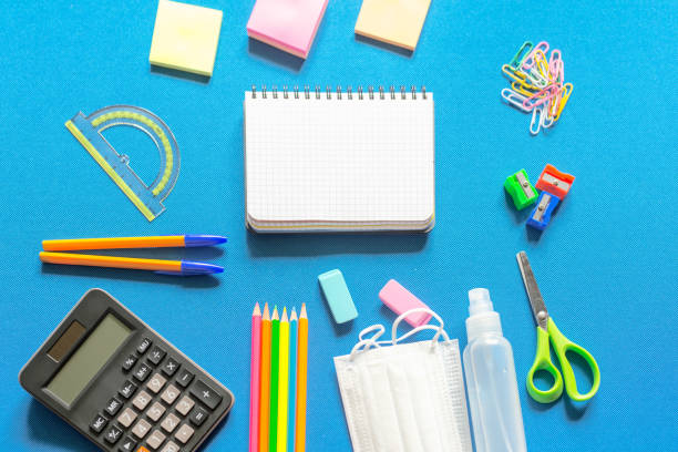 istock Blank graphing paper notebook with school supplies frame against a bright blue wall. Copy space.banner.advertisement. 1803704363