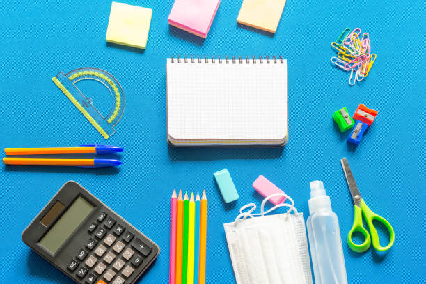 istock Blank graphing paper notebook with school supplies frame against a bright blue wall. Copy space.banner.advertisement. 1803704366