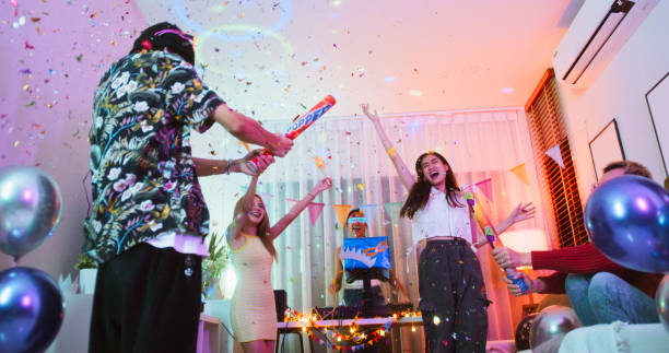 Group of young diverse millennial Asian friends with LGBTQIA+ people dance together at home party, celebrate New Year, Christmas, or Birthday at night. Happy celebration event, fun activity concept un grupo de jóvenes amigos asiáticos millennials diversos con personas lgbtqia+ bailan juntos en una fiesta en casa, celebran el año nuevo, la navidad o el cumpleaños por la noche. feliz evento de celebración, concepto de actividad divertida
