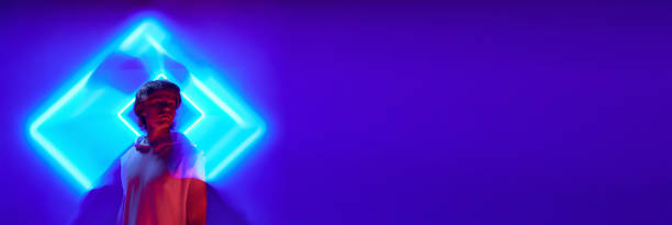 istock Banner. Portrait with long exposure. Young man, guy posing in futuristic, digital projector geometry reflection in vivid neon light. 1803720165