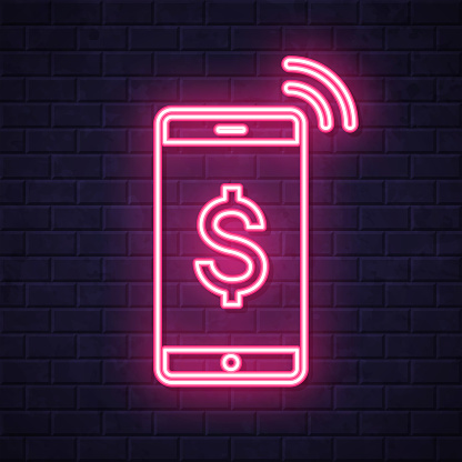 istock Mobile payment with Dollar sign. Glowing neon icon on brick wall background 1803732784