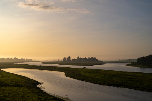 IJssel sunrise panoramic landscape view during a late summer morning near Zwolle. The river on the border of Overijssel and Gelderland is winding into the distance.