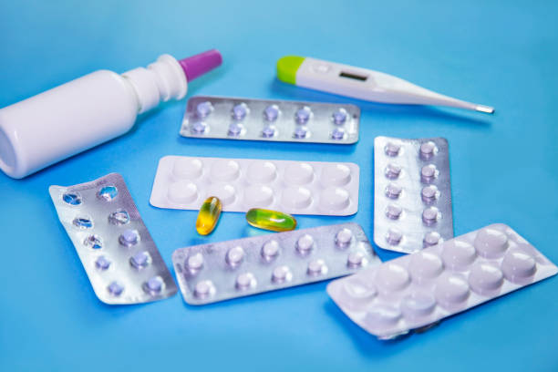 istock Pills and capsules in blister pack and thermometer on blue background 1803745827