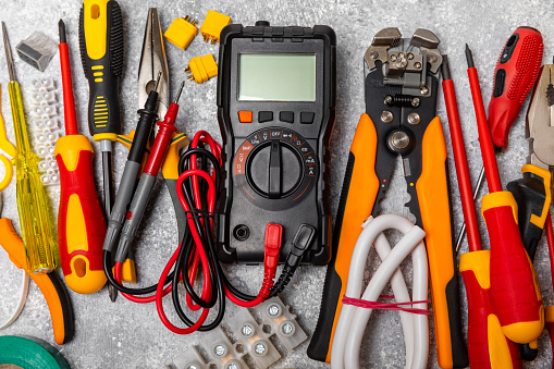 Electrician equipment on marble background with copy space.Top view.Electrician tool set.Multimeter, tester,screwdrivers,cutters,duct tape,lamps,tape measure and wires.Flet lay. Construction concept.