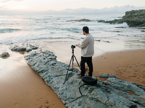 A photographer with a camera on a tripod at a beach. Aerial view