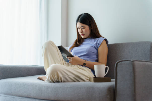 istock Woman holding a book device reading on e-book on digital tablet device or social media apps online ecommerce 1803776190