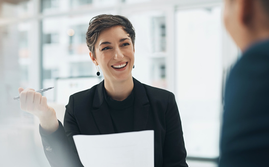 Businesswoman, face and smile with document in office for meeting, planning or collaboration. Female manager, leader and pen in hand for report, review or editing with team for strategy with feedback