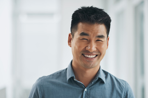 Asian man, portrait or happy in office for business, career growth or positive mindset at corporate job. Entrepreneur, person or employee and smile for project management or sales target at workplace