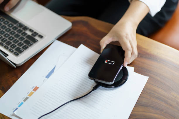 istock Charging mobile phone battery with wireless charging device in the table. Smartphone charging on a charging pad. Mobile phone near wireless charger Modern lifestyle technology concept 1803779934