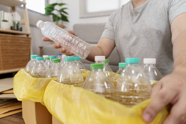 istock Home recycle eco green zero concept Man throwing empty plastic bottle in recycling bin with yellow garbage bags at home 1803780565