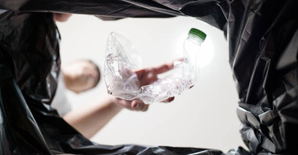 istock Image from inside yellow recycling bag of man throwing empty plastic bottle in recycling bin Home recycle eco green zero concept. 1803780569