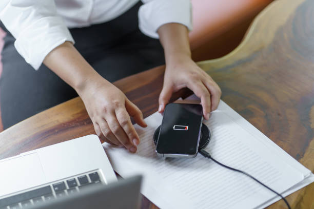 istock Charging mobile phone battery with wireless charging device in the table. Smartphone charging on a charging pad. Mobile phone near wireless charger Modern lifestyle technology concept 1803789070