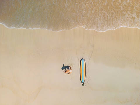 Directly above shot of woman with surfboard on the beach in Bali