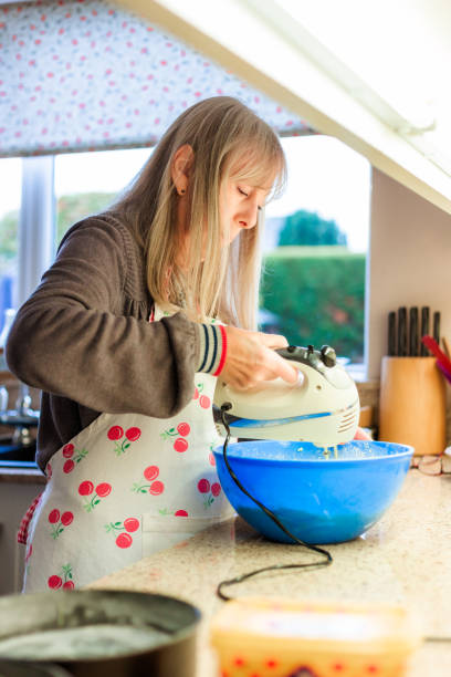 istock Senior woman using electric whisk while making cake in kitchen 1803805888