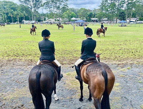 Horizontal landscape of horse riders from back view awaiting their open hunter galloway hack competition in rural country Bangalow show NSW Australia