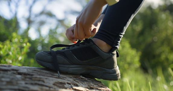 Person, hands and tie shoe for running, fitness or getting ready for cardio workout or outdoor training in nature. Closeup of active sports runner or athlete tying shoes for run, hiking or trekking