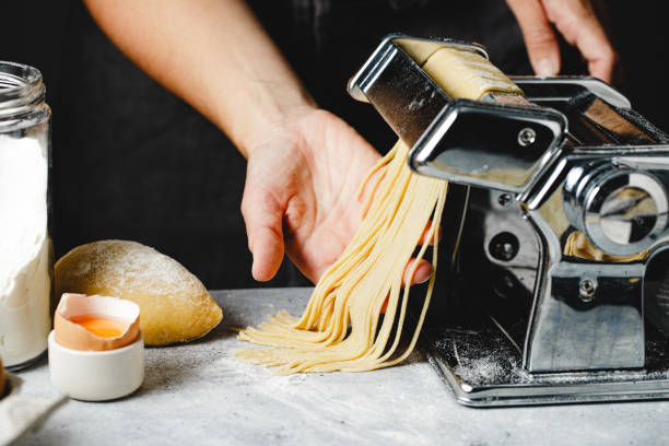 istock Close-up of a woman hands preparing pasta using rolling machine in kitchen 1803824156